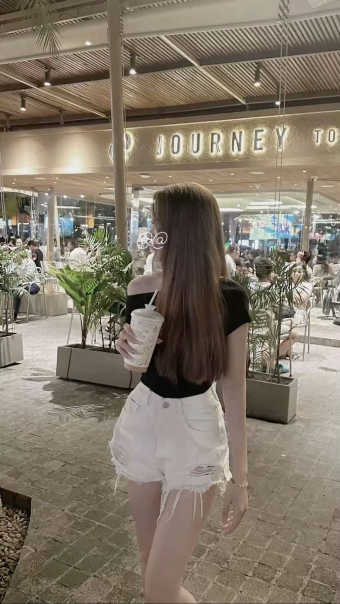 Ảnh cô gái mặc áo phông đen và quần short trắng tại quán cà phê