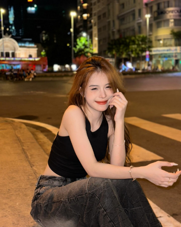 Ảnh cô gái mặc áo tank top đen và quần dài giữa phố đêm