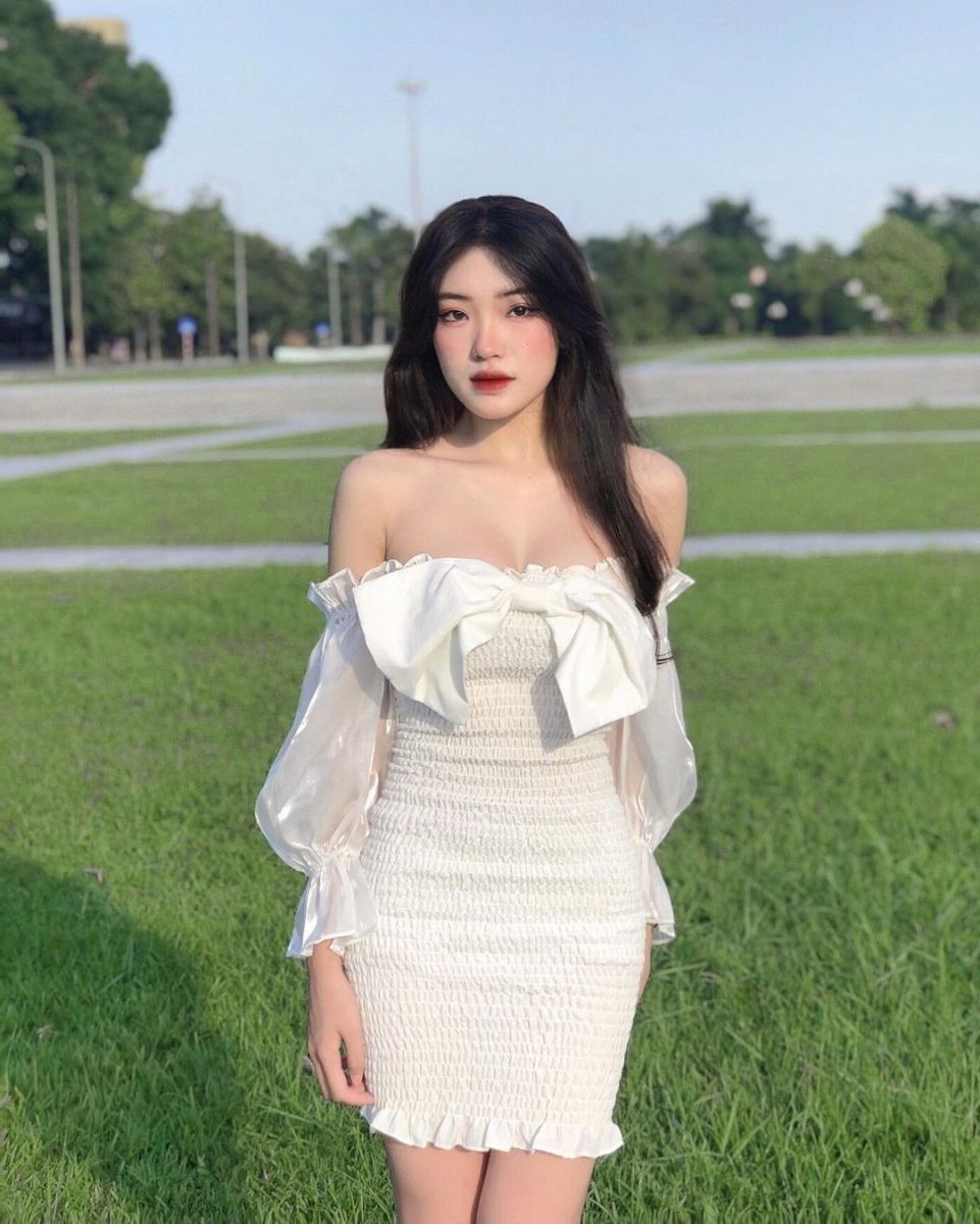Ảnh cô gái mặc váy trắng ôm sát cổ tay áo voan trên cỏ xanh