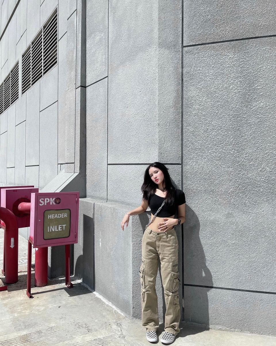 Ảnh cô gái trẻ mặc áo crop top đen và quần cargo màu be
