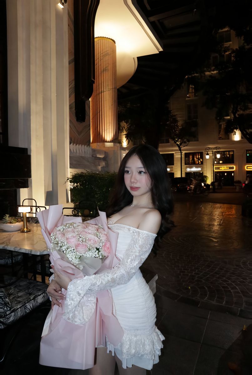 Ảnh cô gái trẻ mặc váy trắng ôm bó hoa hồng
