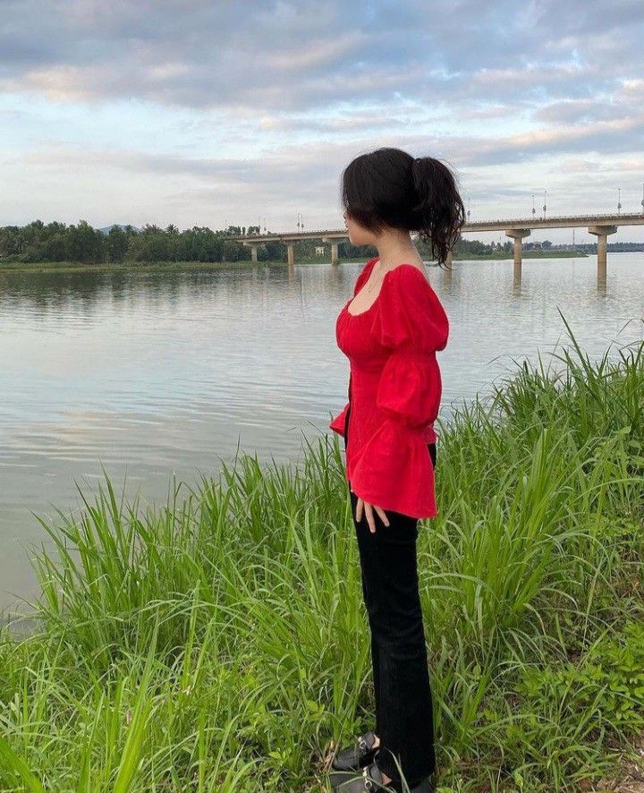 Ảnh gái trẻ mặc áo đỏ và quần đen bên bờ sông