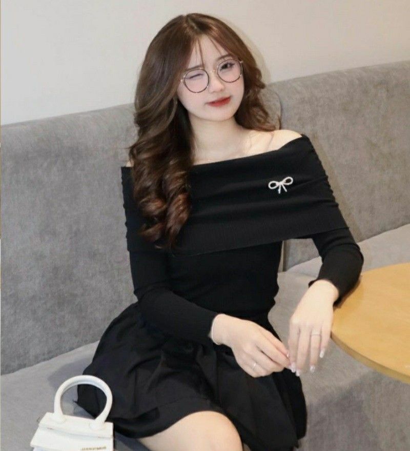 Ảnh gái trẻ mặc áo thun đen và chân váy đen ngồi trên ghế sofa