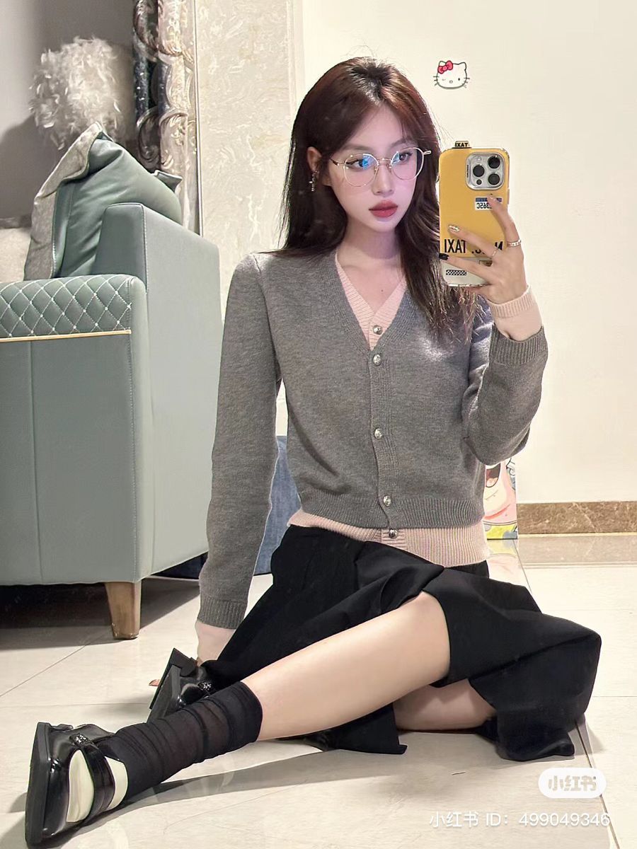 Ảnh gái trẻ ngồi trên nền gạch mặc áo khoác cardigan xám