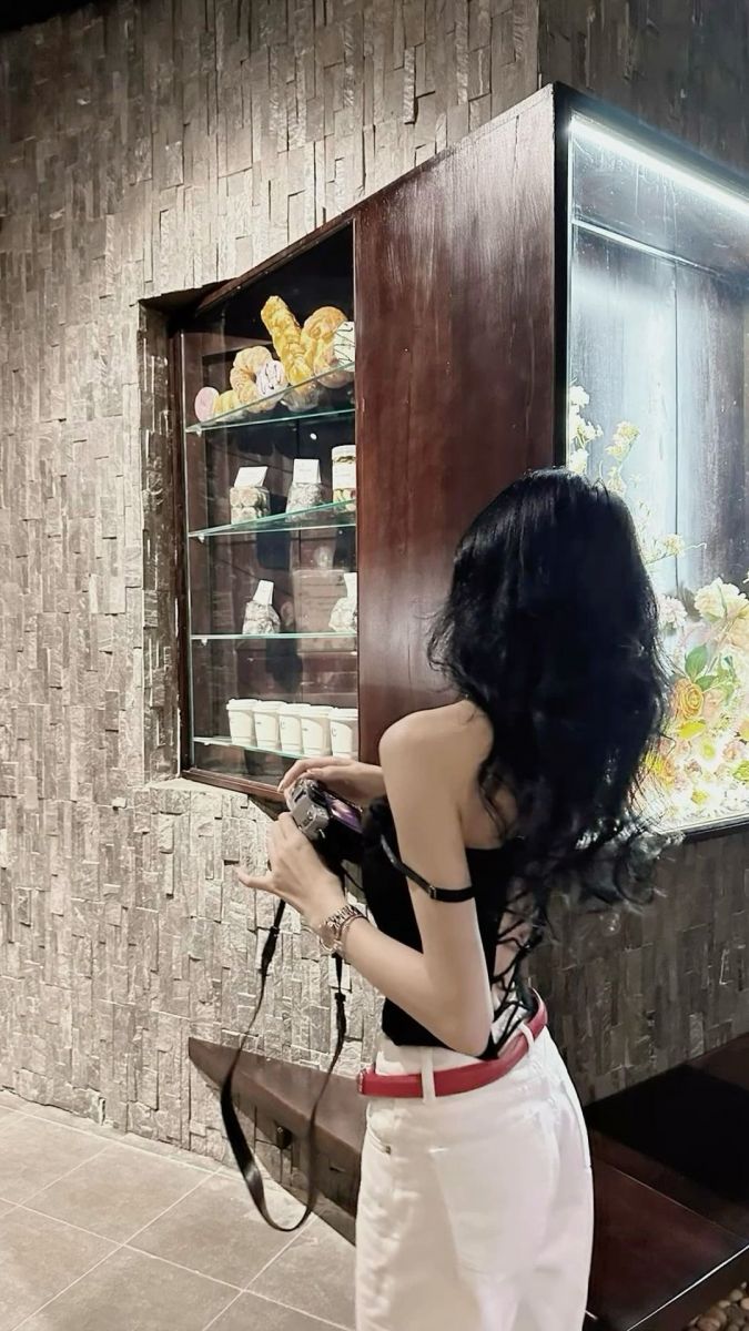 Ảnh gái xinh mặc áo đen và quần trắng chụp hình trong cửa hàng bánh ngọt