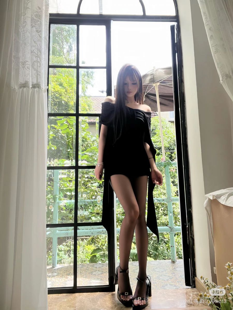 Cô gái đẹp mặc váy đen bên cửa sổ, tự tin với đôi giày cao gót