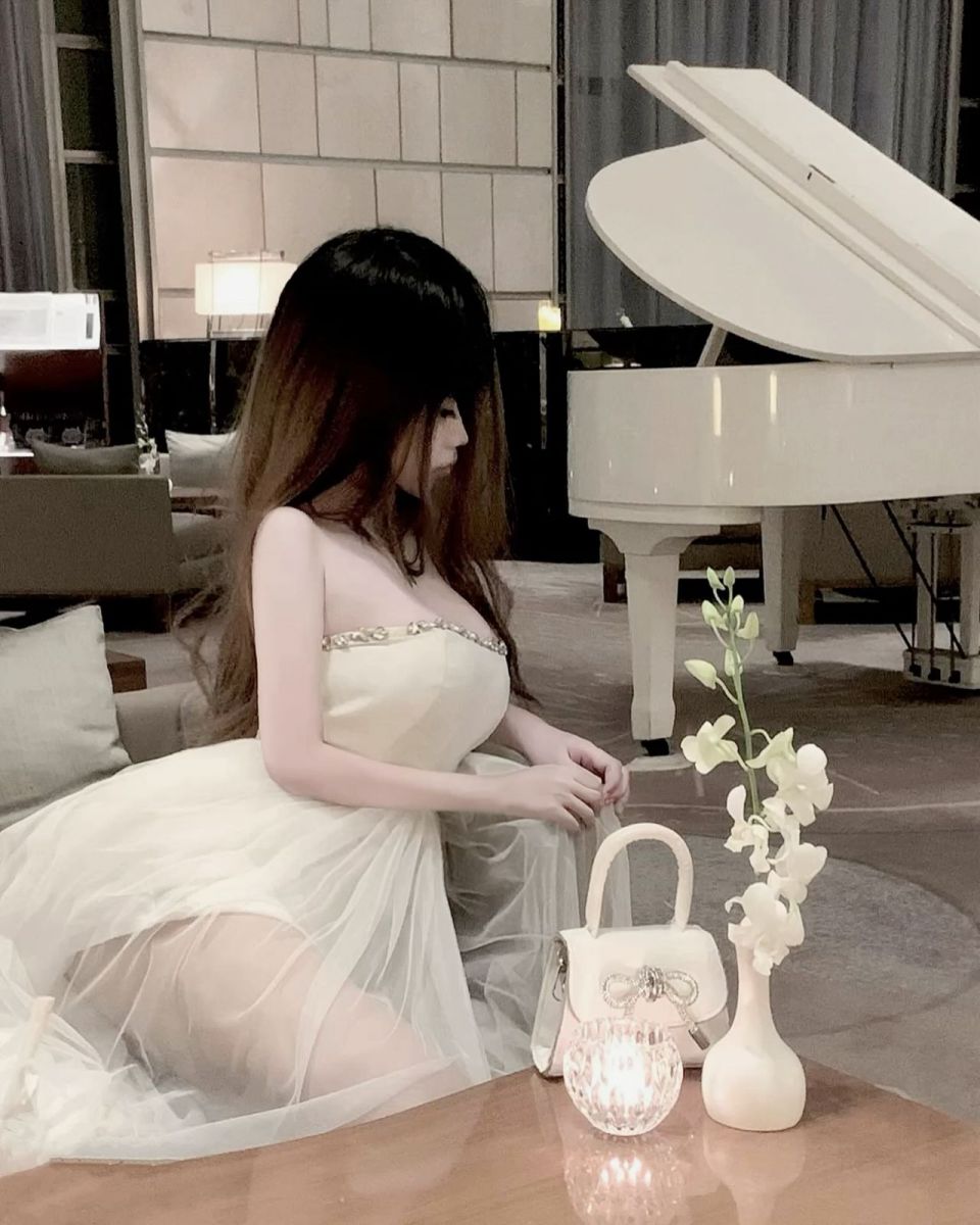 Cô gái đẹp mặc váy trắng bên đàn piano sang trọng