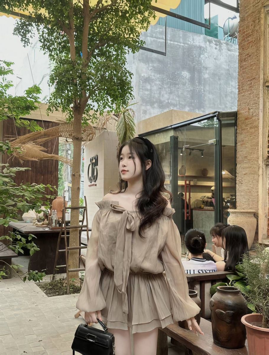 Cô gái mặc áo blouse mỏng màu beige trong quán cà phê