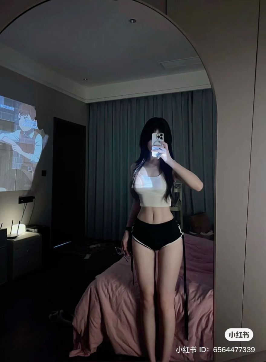 Cô gái mặc áo crop top trắng và quần short đen trong phòng ngủ