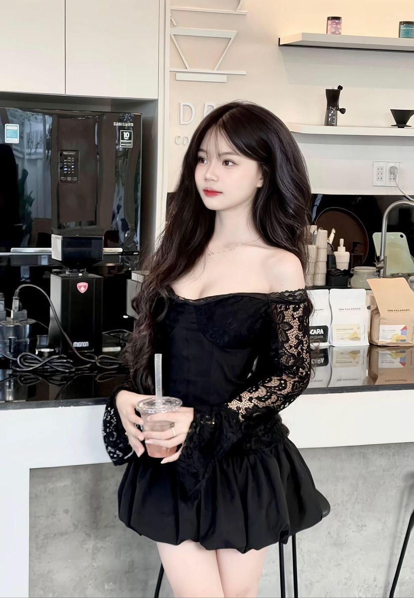 Cô gái mặc áo đen tay dài và váy xòe trong quán cà phê hiện đại