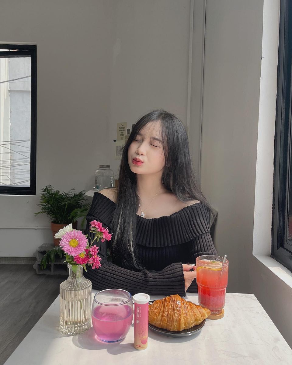 Cô gái mặc áo len màu đen bên bàn ăn trong quán cà phê