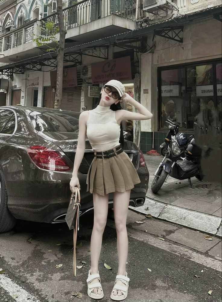 Cô gái mặc áo ống trắng kết hợp chân váy ngắn màu nâu bên xe ô tô