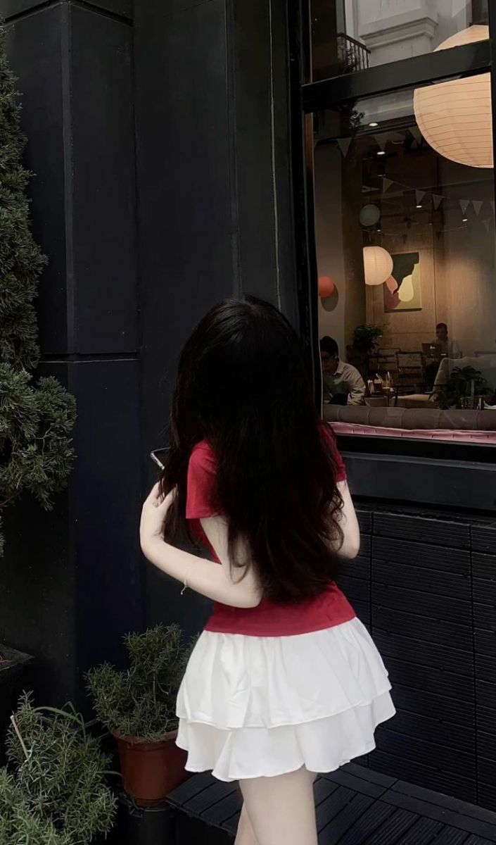Cô gái mặc áo phông đỏ và chân váy trắng tại quán cà phê