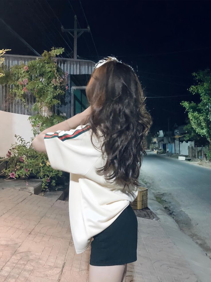 Cô gái mặc áo phồng trắng và quần shorts đen bên cây cối