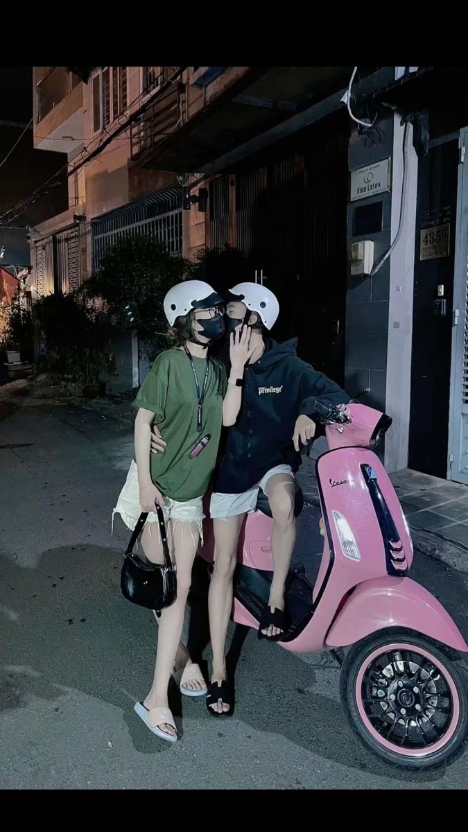 Cô gái mặc áo phông xanh và quần jeans rách bên chàng trai trong hoodie đen