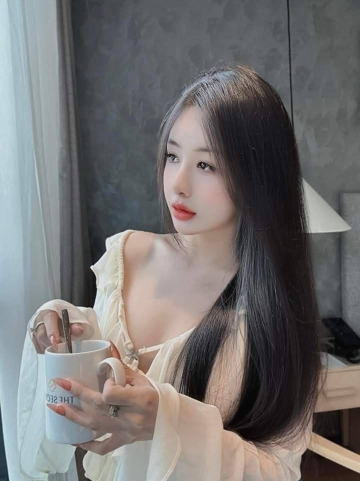 Cô gái mặc áo sơ mi trắng ngồi bên cửa sổ trong không gian phòng khách