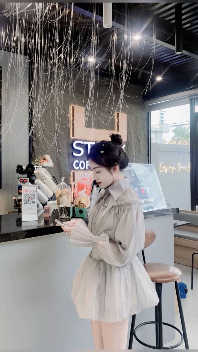 Cô gái mặc áo tay bồng màu xám bên quầy bar