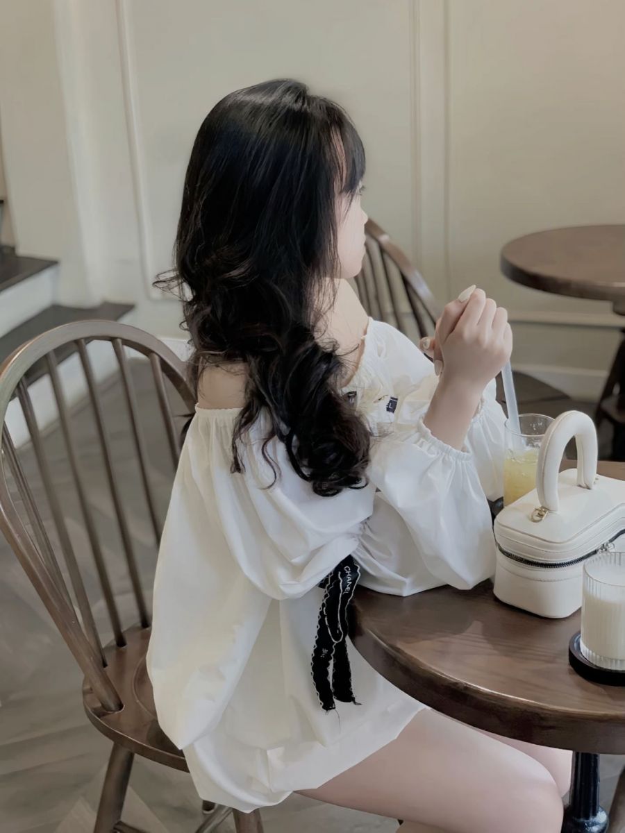 Cô gái mặc áo trắng ngồi ở quán cà phê thư giãn