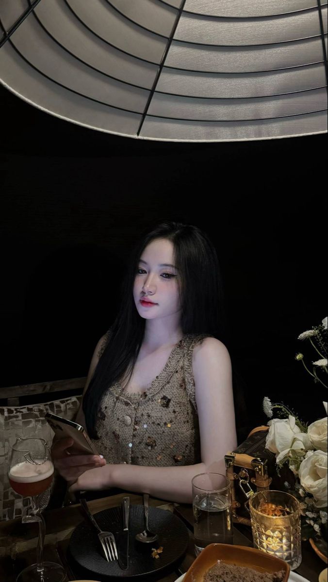 Cô gái mặc áo vest màu nâu ngồi trên bàn ăn sang trọng