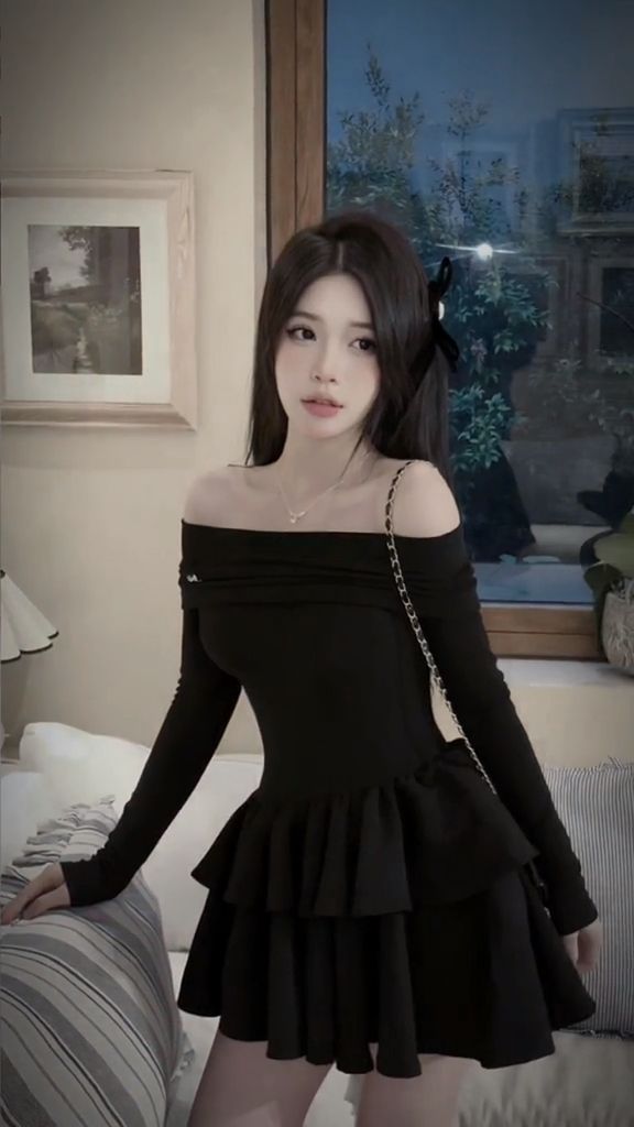 Cô gái mặc đầm đen ôm sát với chân váy xòe tạo dáng trong một căn phòng sang trọng