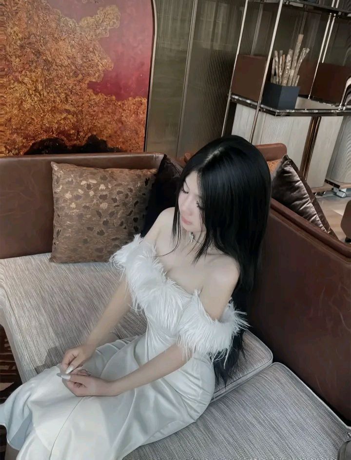 Cô gái mặc đầm trắng thanh lịch trên ghế sofa sang trọng