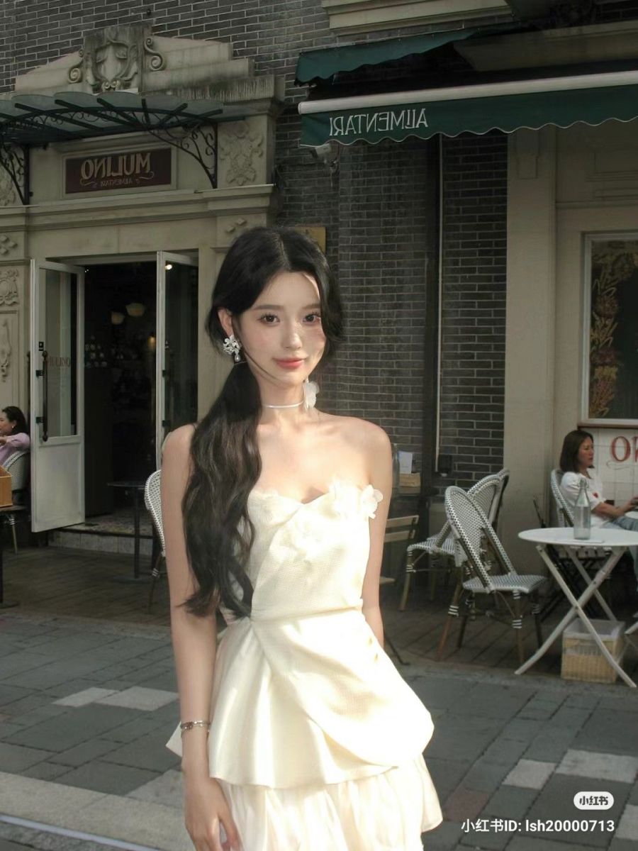 Cô gái mặc đầm trắng tự tin bên quán cà phê ngoài trời