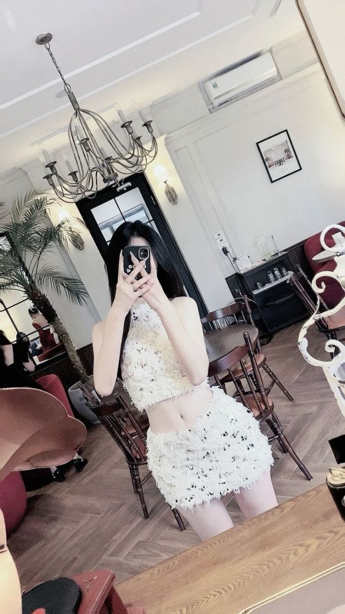 Cô gái mặc trang phục trắng tinh tế chụp ảnh tự sướng trong không gian nội thất