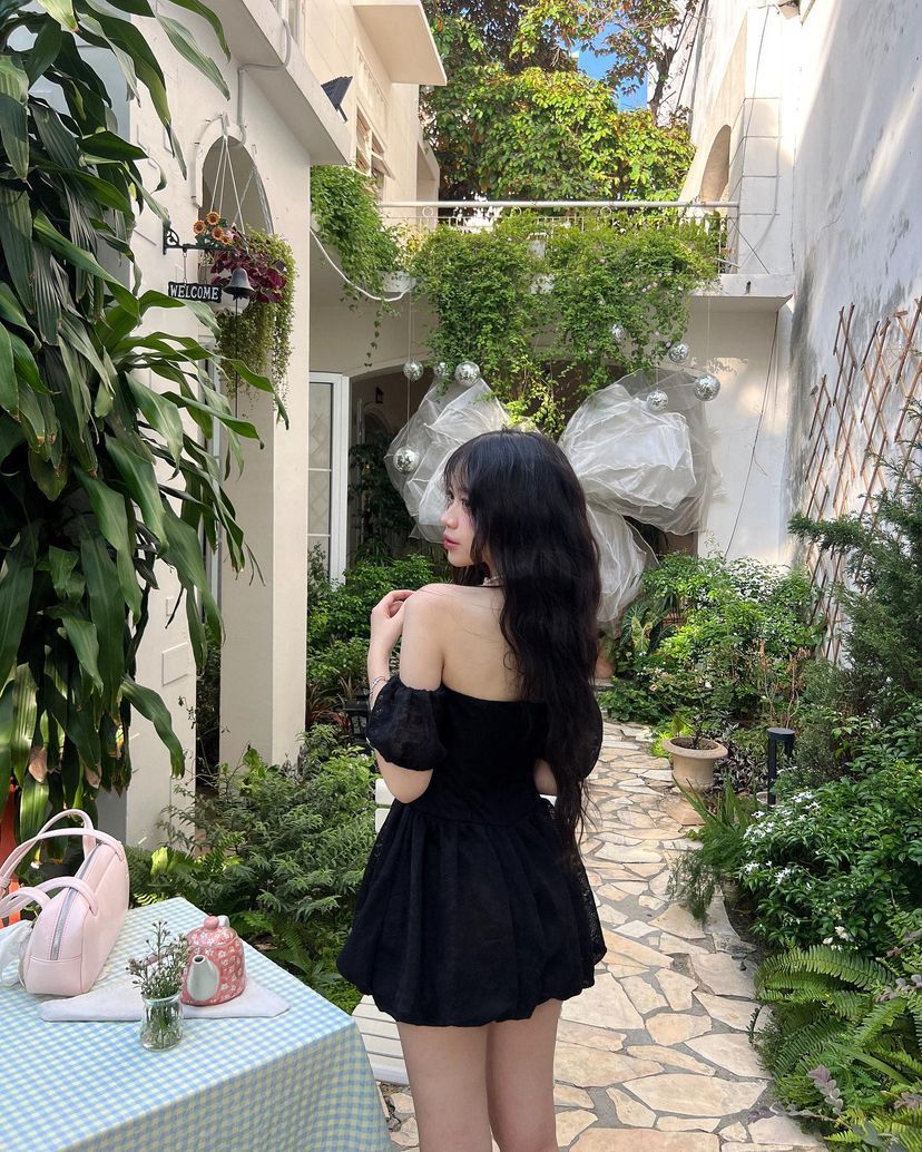Cô gái mặc váy đen off-shoulder giữa vườn xanh tươi