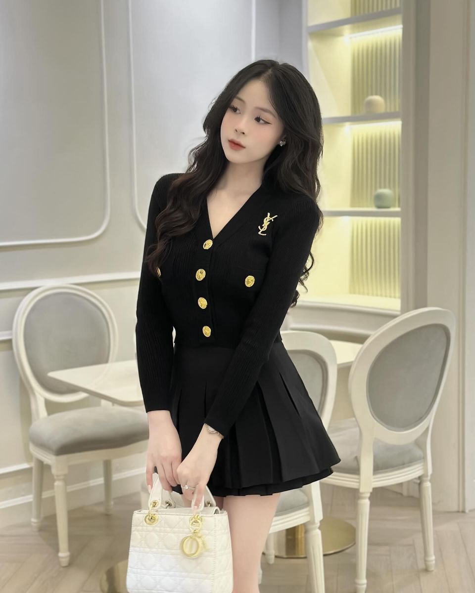 Cô gái mặc váy ngắn phối áo len tay dài và túi xách trắng