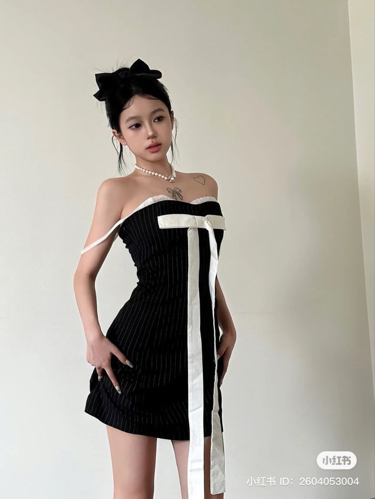 Cô gái mặc váy ngắn tay màu đen sọc trắng trong căn phòng sáng màu táo