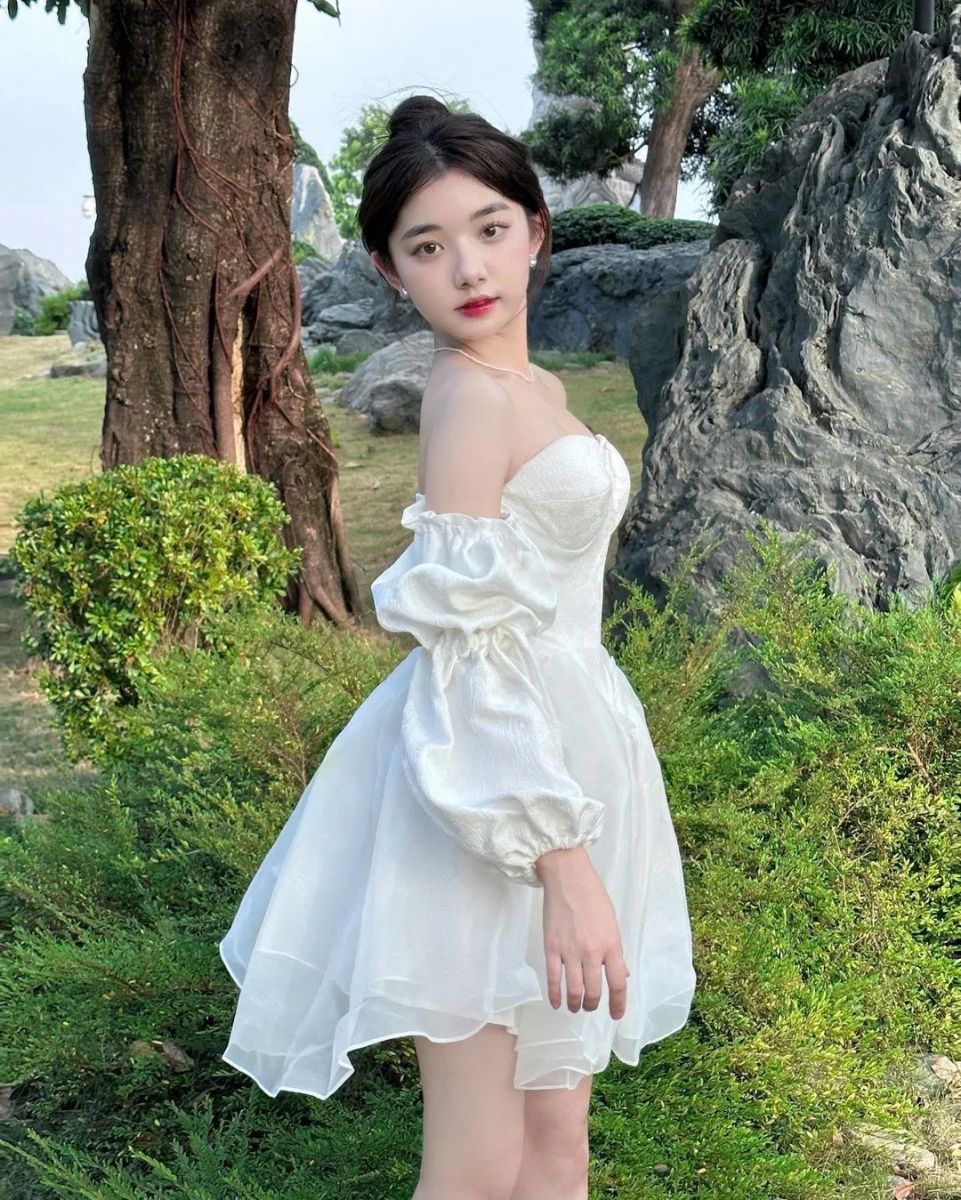 Cô gái mặc váy trắng bên cây xanh mát