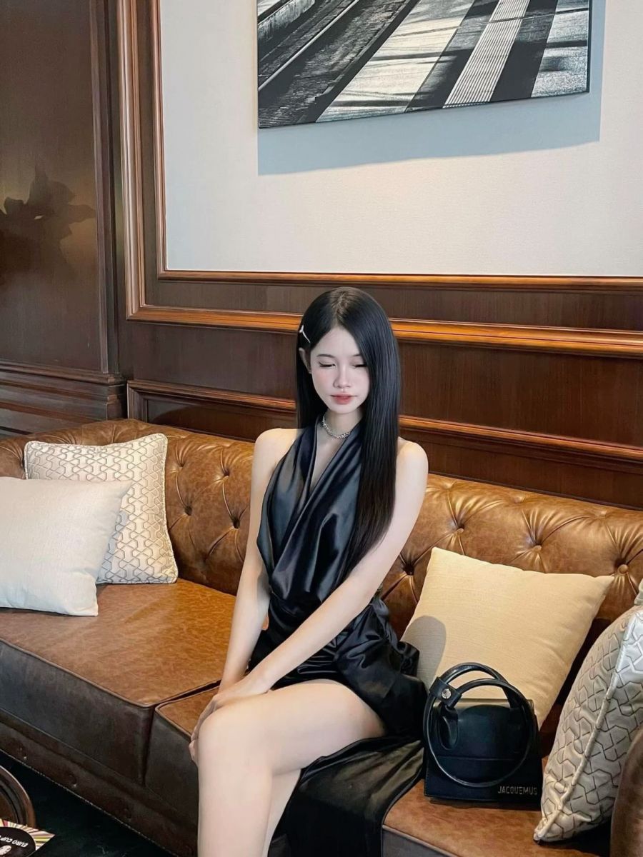 Cô gái mặc váy trắng ngồi trên ghế sofa da sang trọng