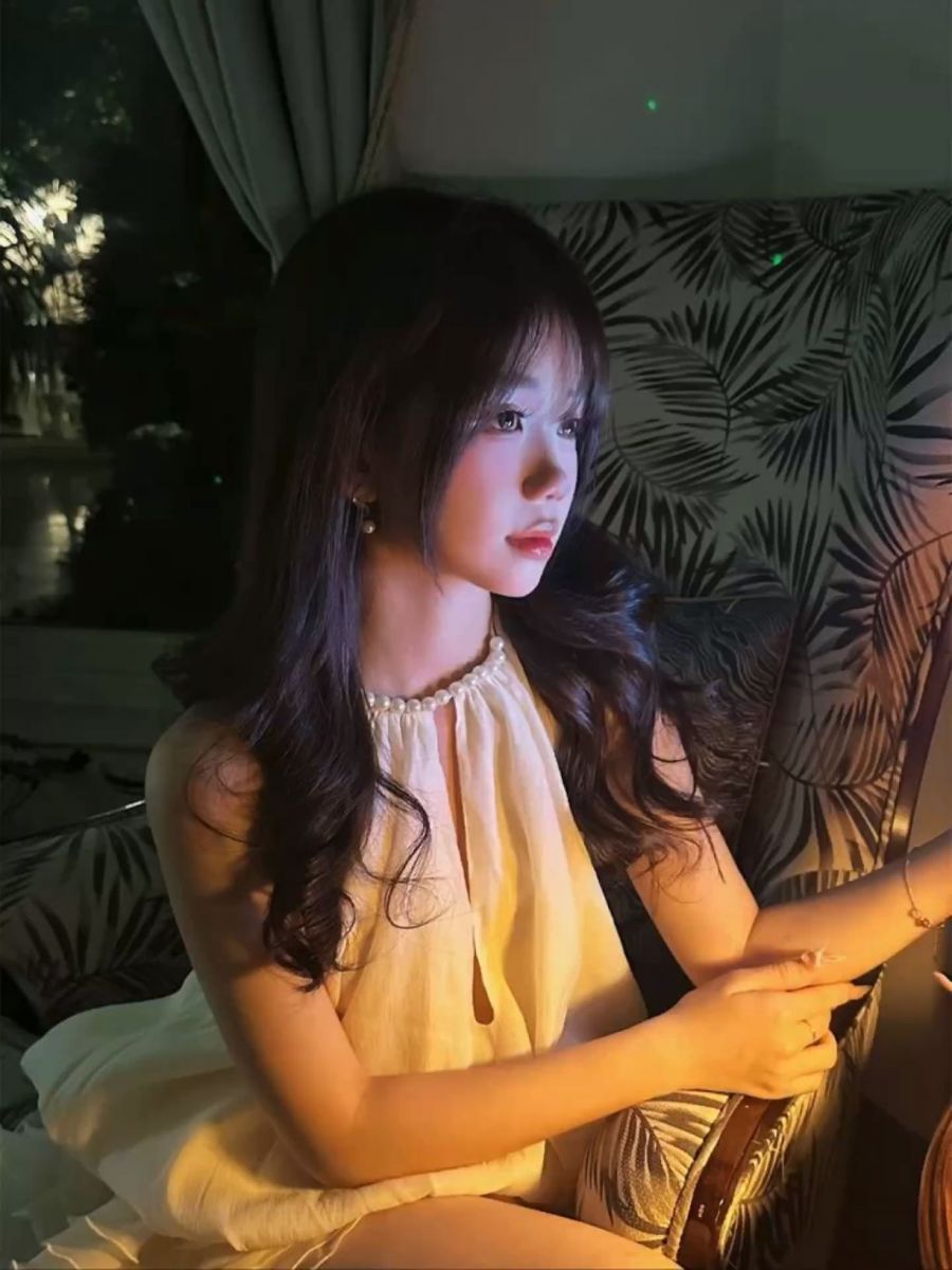 Cô gái mặc váy trắng ngồi trên ghế tạo dáng thư giãn
