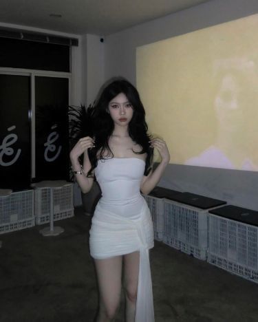 Cô gái mặc váy trắng tạo dáng trước màn hình chiếu