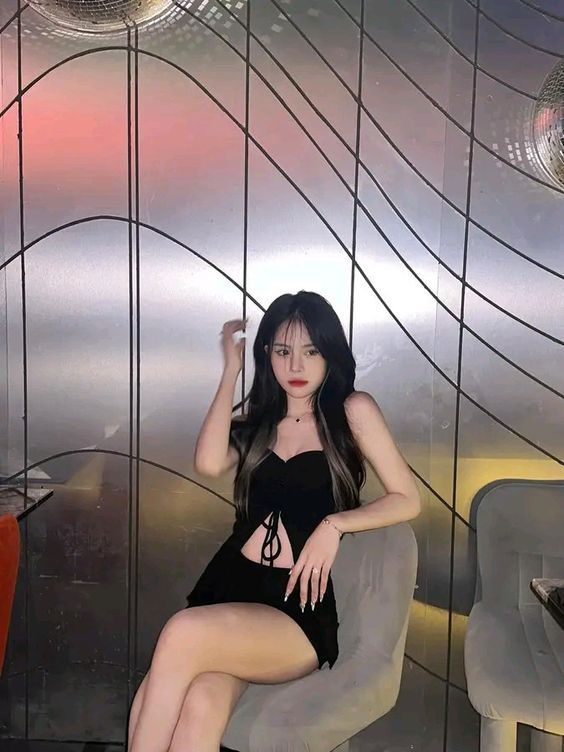 Cô gái quyến rũ trong trang phục đen tự tin ngồi trên ghế