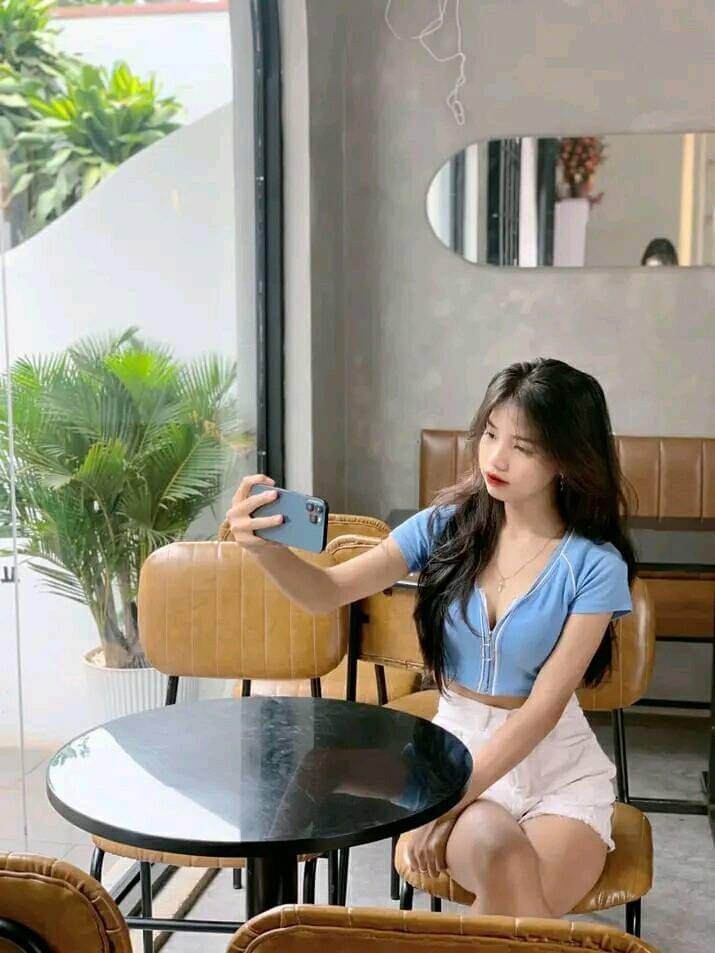 Cô gái trẻ chụp selfie xinh xắn trong quán cà phê