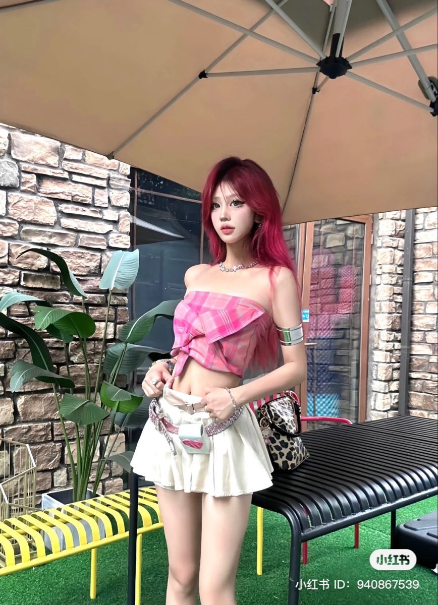 Cô gái trẻ diện áo crop top caro hồng và váy ngắn trắng tại quán cà phê