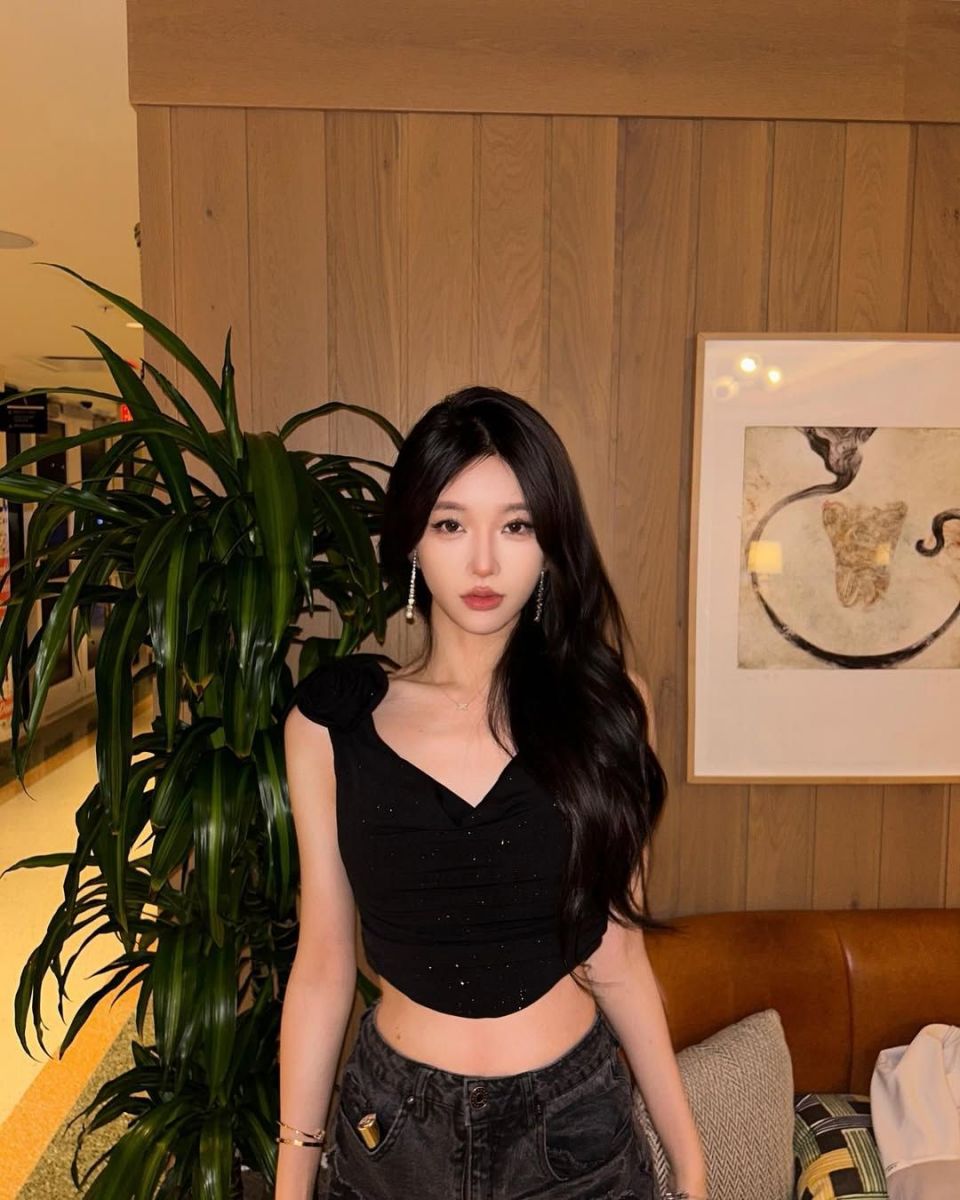 Cô gái trẻ diện áo croptop đen và quần jeans giữa không gian xanh