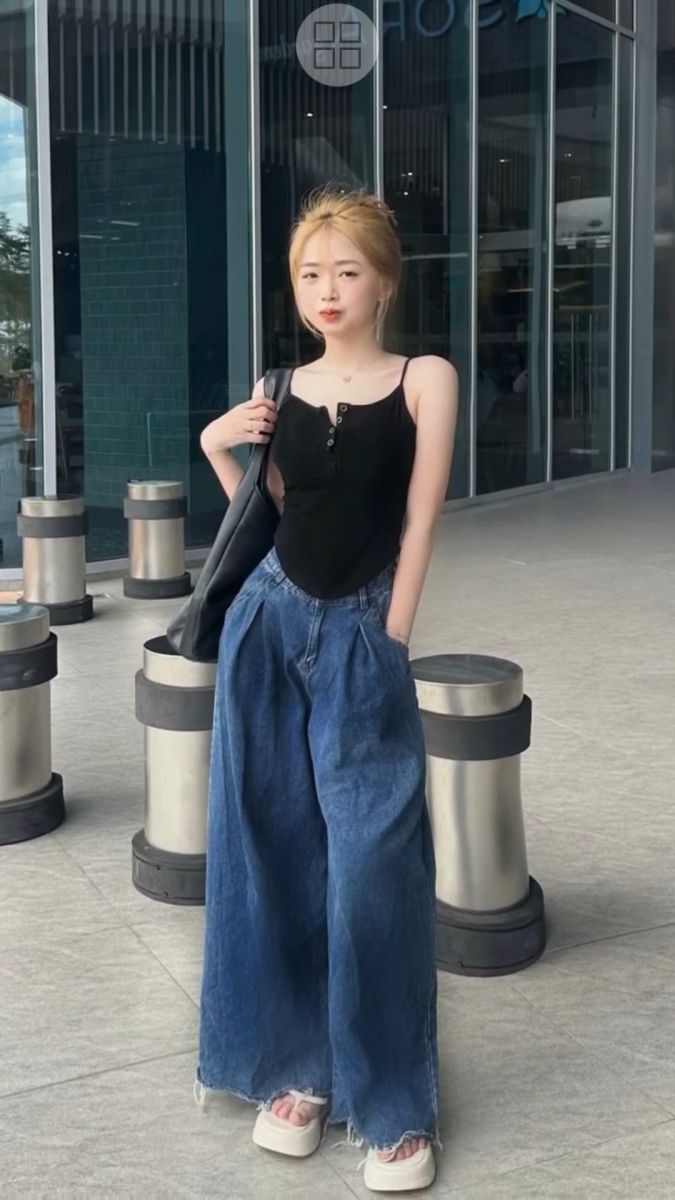 Cô gái trẻ mặc áo ba lô đen và quần jeans rộng