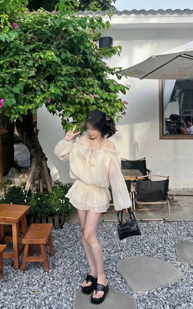 Cô gái trẻ mặc áo blouse trắng và chân váy ngắn giữa khu vườn xanh tươi