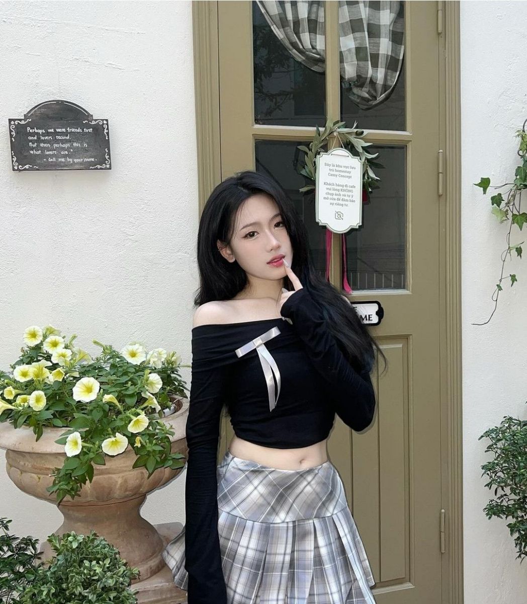 Cô gái trẻ mặc áo crop top đen bên chân váy kẻ caro