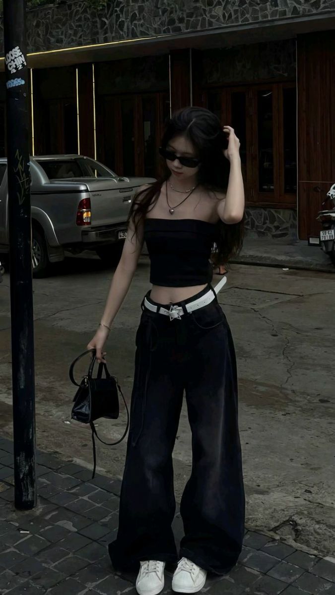 Cô gái trẻ mặc áo crop top đen và quần rộng