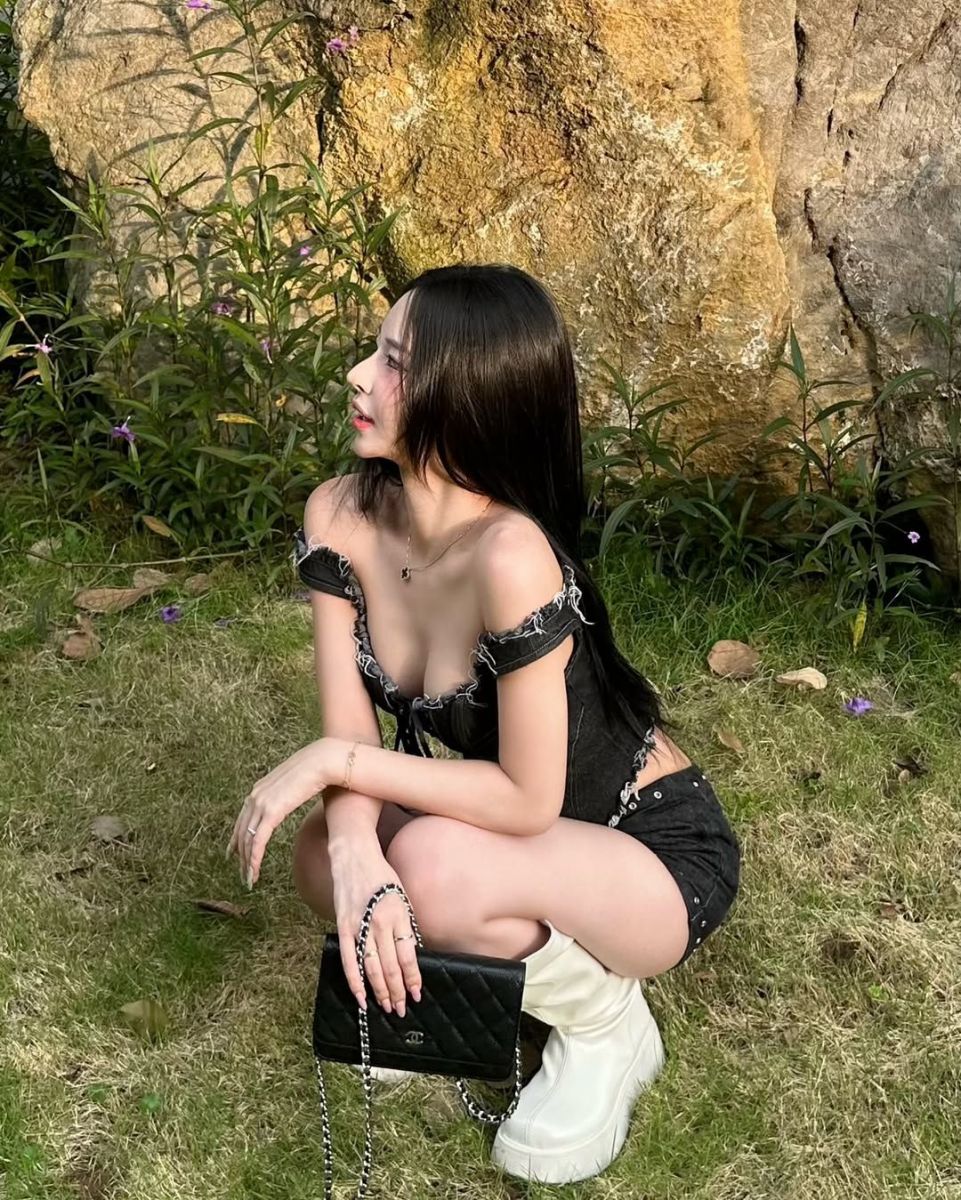 Cô gái trẻ mặc áo crop top đen và quần short ngồi tạo dáng