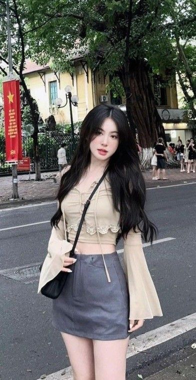 Cô gái trẻ mặc áo crop top màu be và chân váy ngắn trên phố đông người