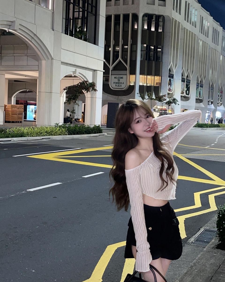 Cô gái trẻ mặc áo crop top trắng và chân váy ngắn đen giữa phố