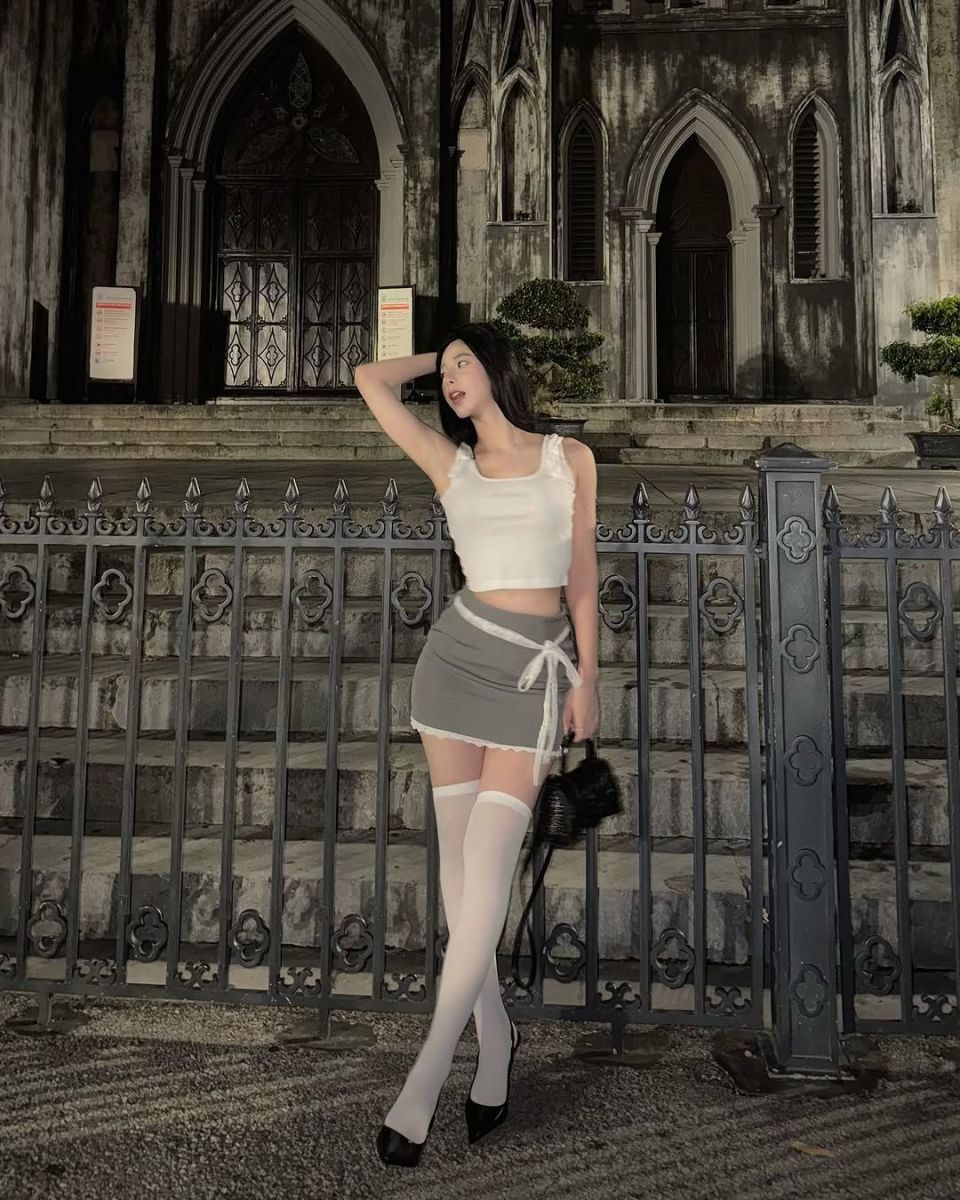 Cô gái trẻ mặc áo crop top trắng và chân váy xám đẹp mắt