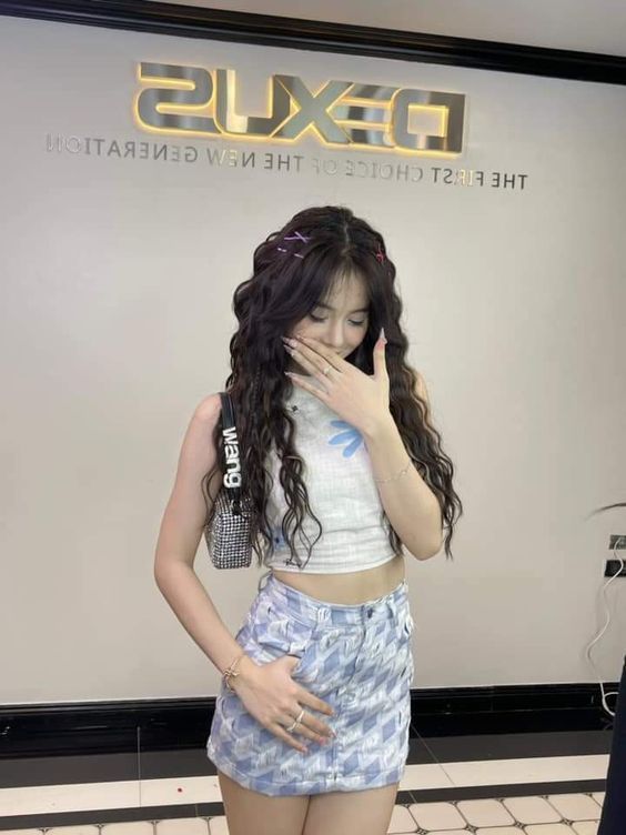 Cô gái trẻ mặc áo crop top trắng và váy ngắn xanh hoa tiết