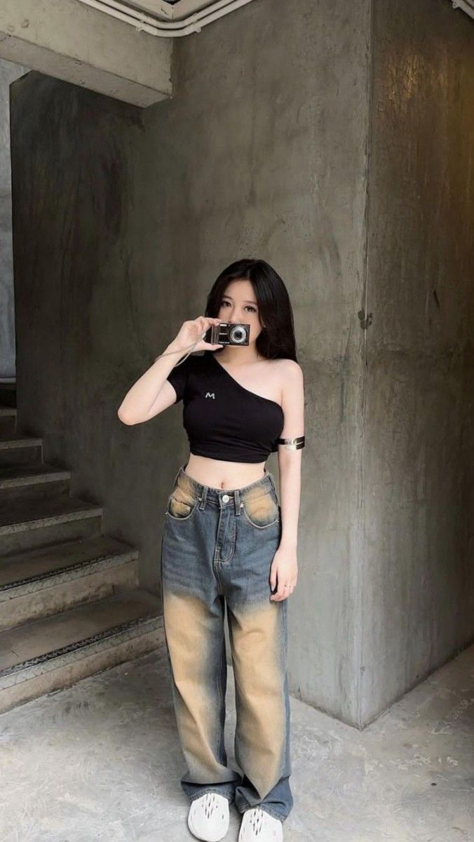 Cô gái trẻ mặc áo cropped màu đen và quần jeans rộng
