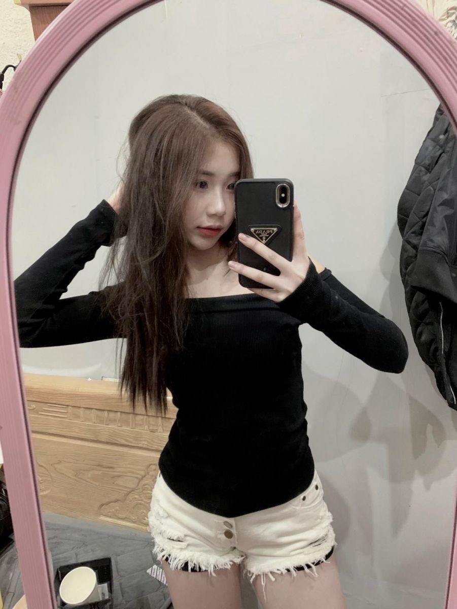 Cô gái trẻ mặc áo dài tay đen và quần short trắng