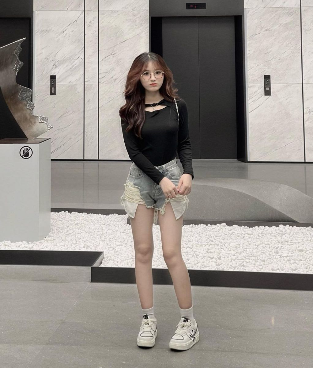 Cô gái trẻ mặc áo dài tay màu đen và quần shorts jeans